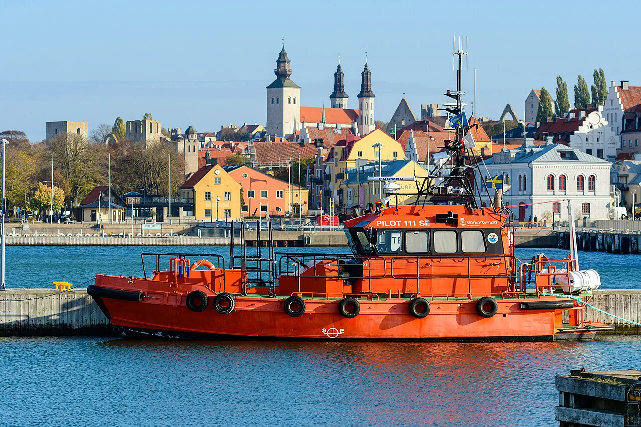 A pilot boat in Visby harbour with the old town behind.